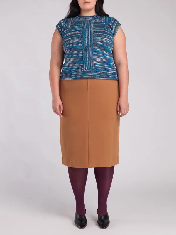 A model is pictured, wearing LISA AVIVA's Hand Knit Top with Raglan Sleeves, in Arctic Ocean and the Pebbled Wool Skirt, in Skaha Beach.